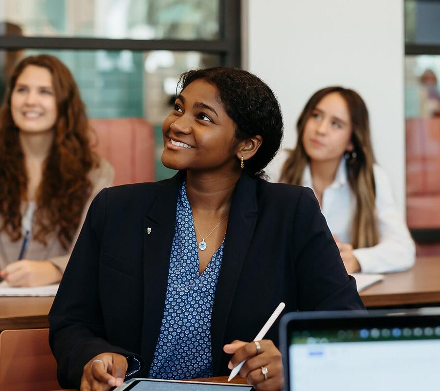 female students smiling 和 taking notes at 推荐全球最大网赌正规平台欢迎您